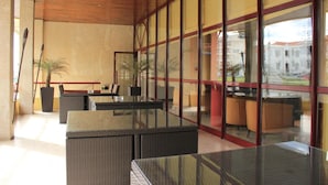 Un espacio interior moderno con paredes de vidrio, muebles de mimbre y techo de madera.