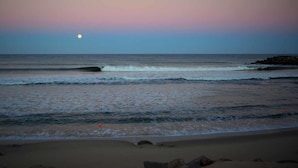 Una playa con olas y una luna en el cielo.