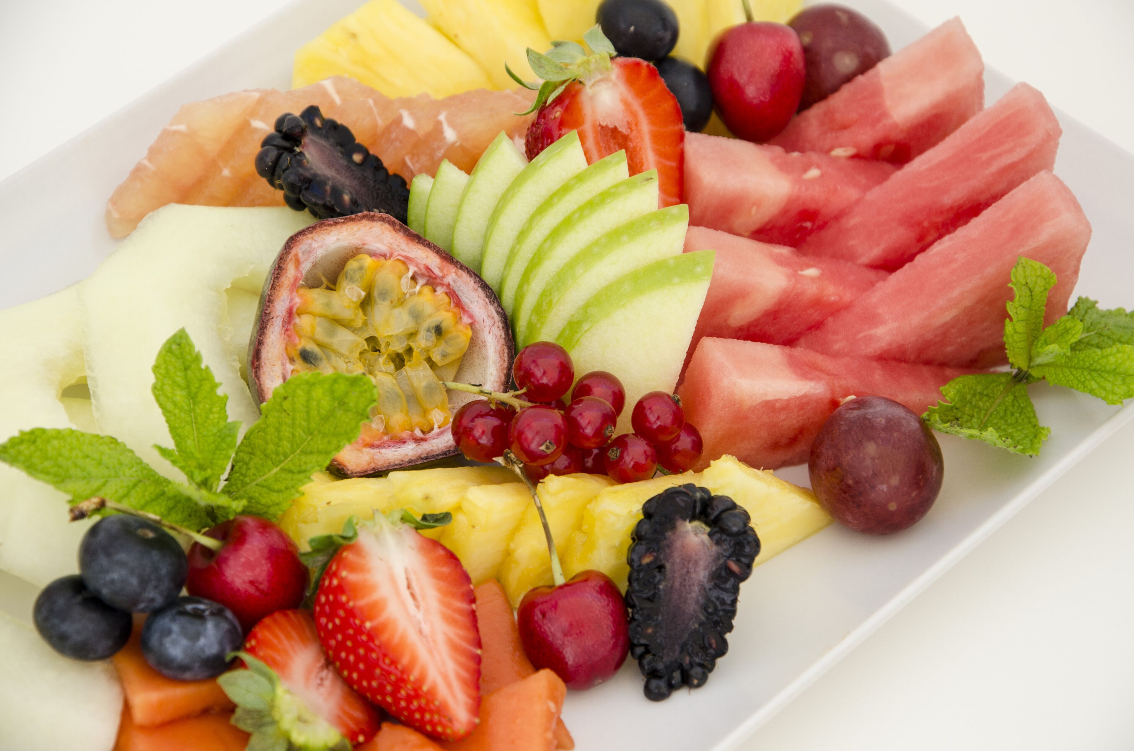 Una variedad de frutas frescas como sandía, fresas, uvas y manzanas dispuestas sobre un plato blanco.