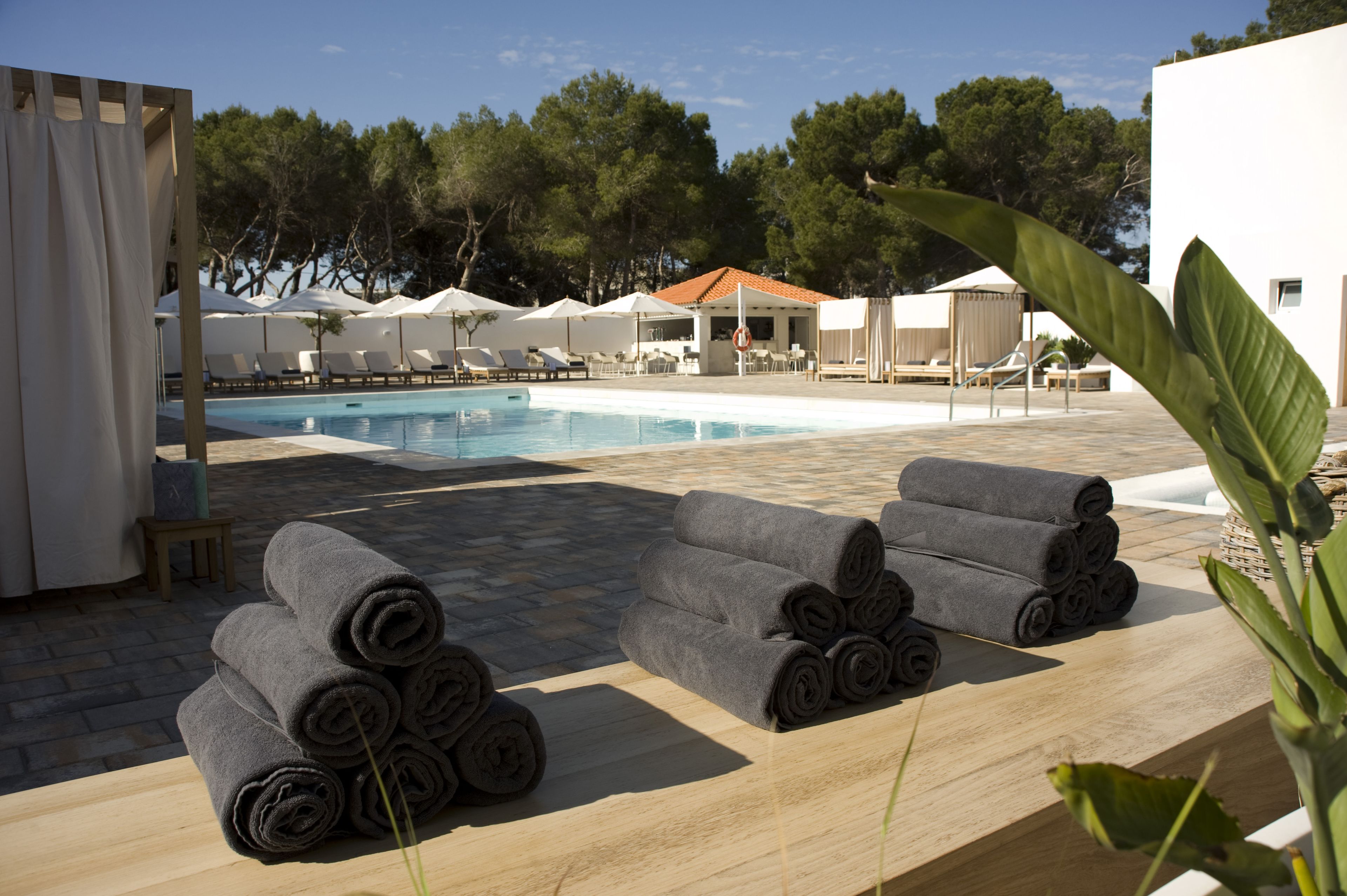 Zona junto a la piscina con sillones de descanso, una piscina y un área de estar techada.