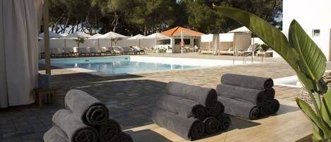 Zona junto a la piscina con sillones de descanso, una piscina y un área de estar techada.