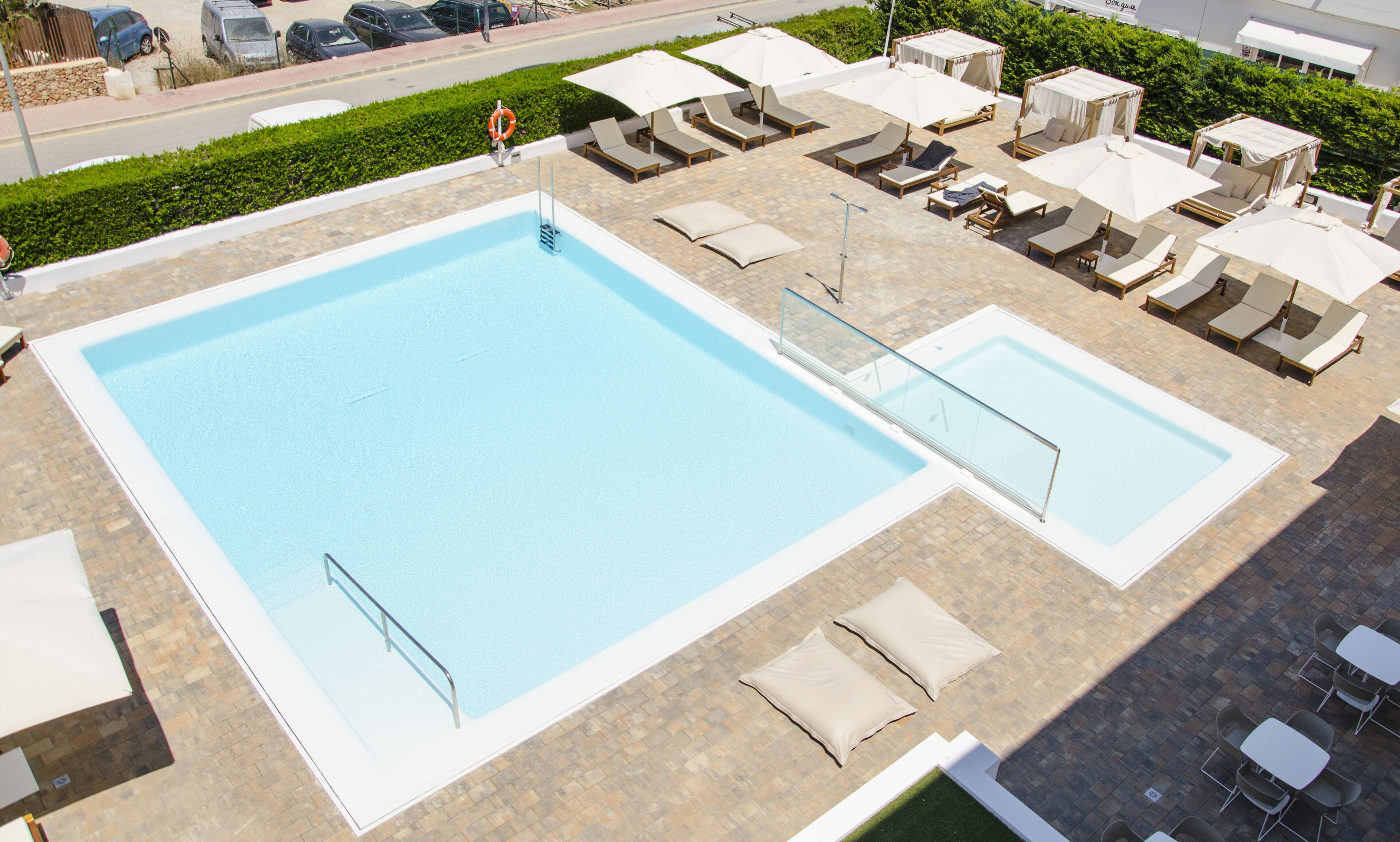 Ein großer rechteckiger Pool mit einer gefliesten Liegefläche, ausgestattet mit Liegestühlen und Sonnenschirmen.
