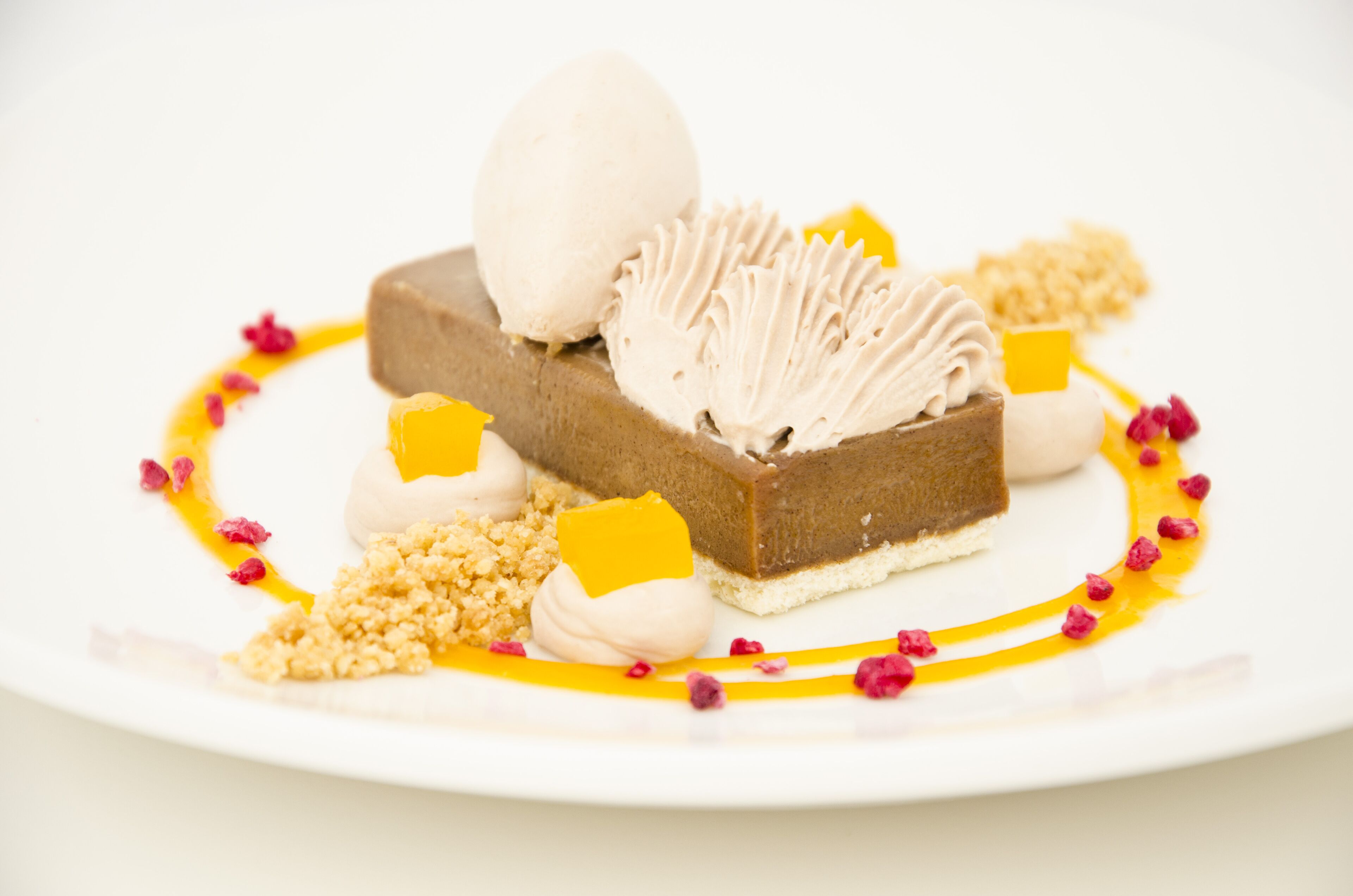 Ein Dessertteller mit Schokoladenkuchen, einer Kugel Eis und dekorativen Elementen.