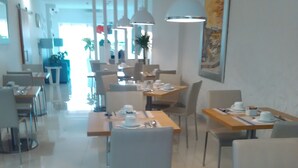 A modern dining area with tables and chairs, a large painting on the wall, and a bright interior. - Sea Garden Residência (Peniche)