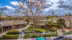 A parking area with a 'P' sign, a green-roofed building, and a tree-lined pathway. - Sea Garden Residência (Peniche)