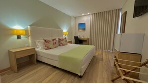 A hotel room with a bed, bedside tables, a desk, a chair, a TV, and a wardrobe. - Sea Garden Residência (Peniche)