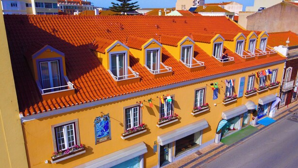 A yellow building with orange tiled roofs, multiple windows, and balconies. - Sea Garden Residência (Peniche)
