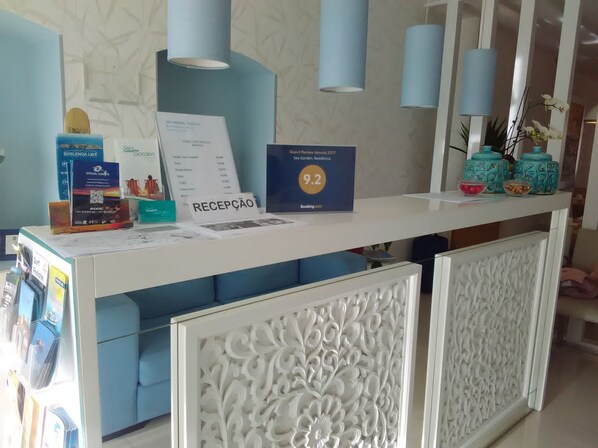 Un comptoir d’accueil avec une pancarte indiquant une note de 9,2, un tableau affichant le menu et un espace détente avec des sièges bleus et confortables.