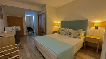 Una habitación de hotel con una cama, mesitas de noche, un escritorio, una silla y una botella de agua.