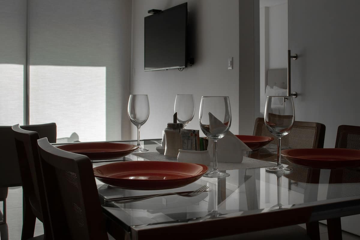 A dining table with red plates, wine glasses, and cutlery.