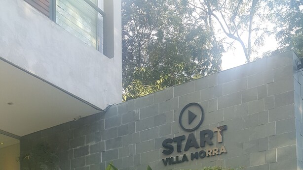 Eine Treppe führt zu einem Gebäude, an dem ein Schild mit der Aufschrift „START VILLA NORMA“ steht.