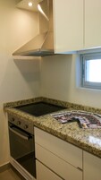 Una cocina compacta con encimera de granito, horno de acero inoxidable y una ventana sobre el fregadero.
