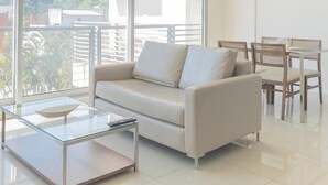 Ein modernes Wohnzimmer mit einer Couch, einem Glastisch und einem Essbereich.