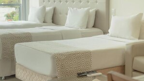 Ein modernes Hotelzimmer mit zwei Betten, einem Glastisch und Blick auf Grünflächen.