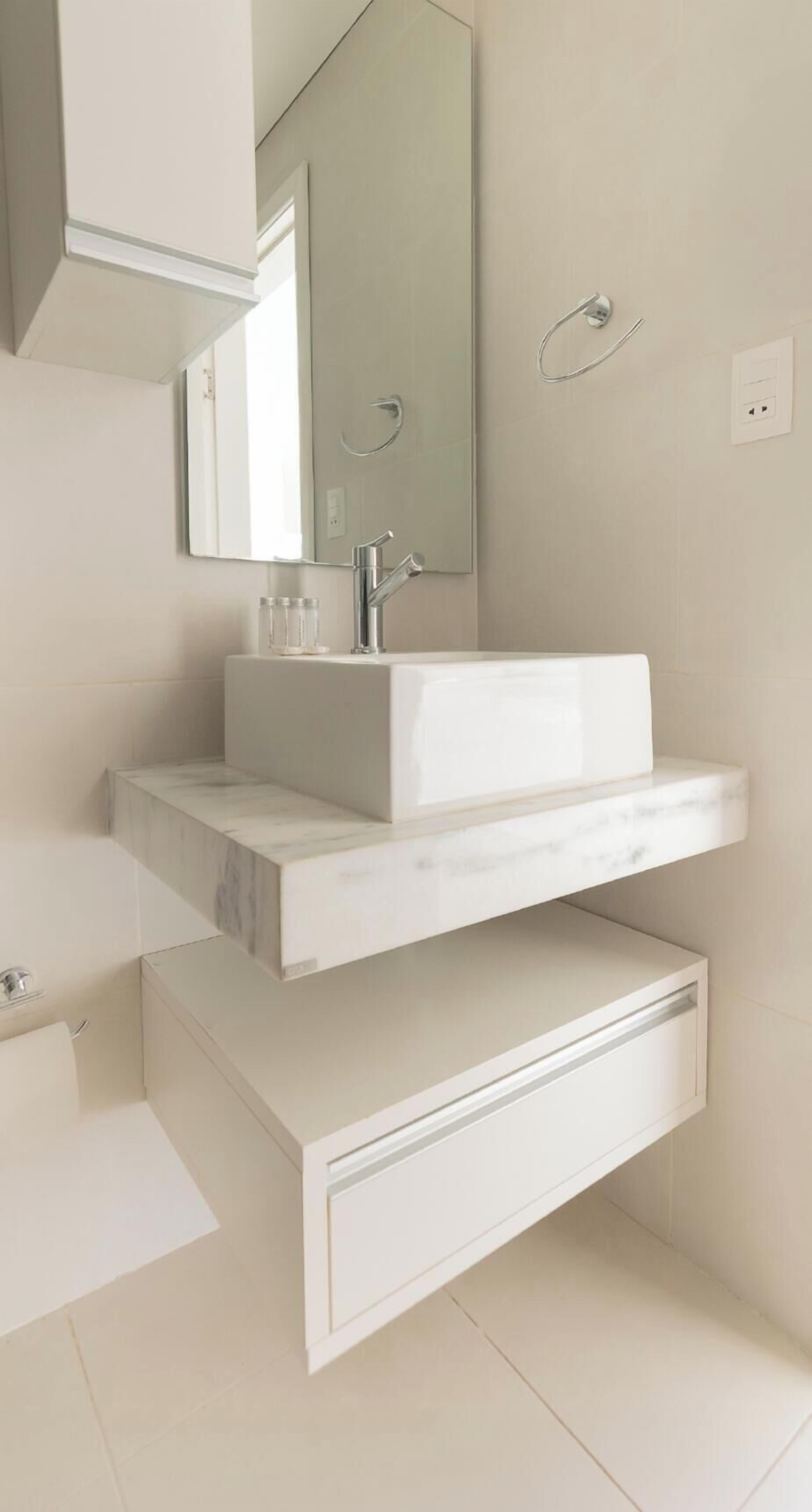A modern bathroom with a white vanity, a large mirror, and a built-in sink.