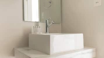 A modern bathroom with a white vanity, a large mirror, and a built-in sink.