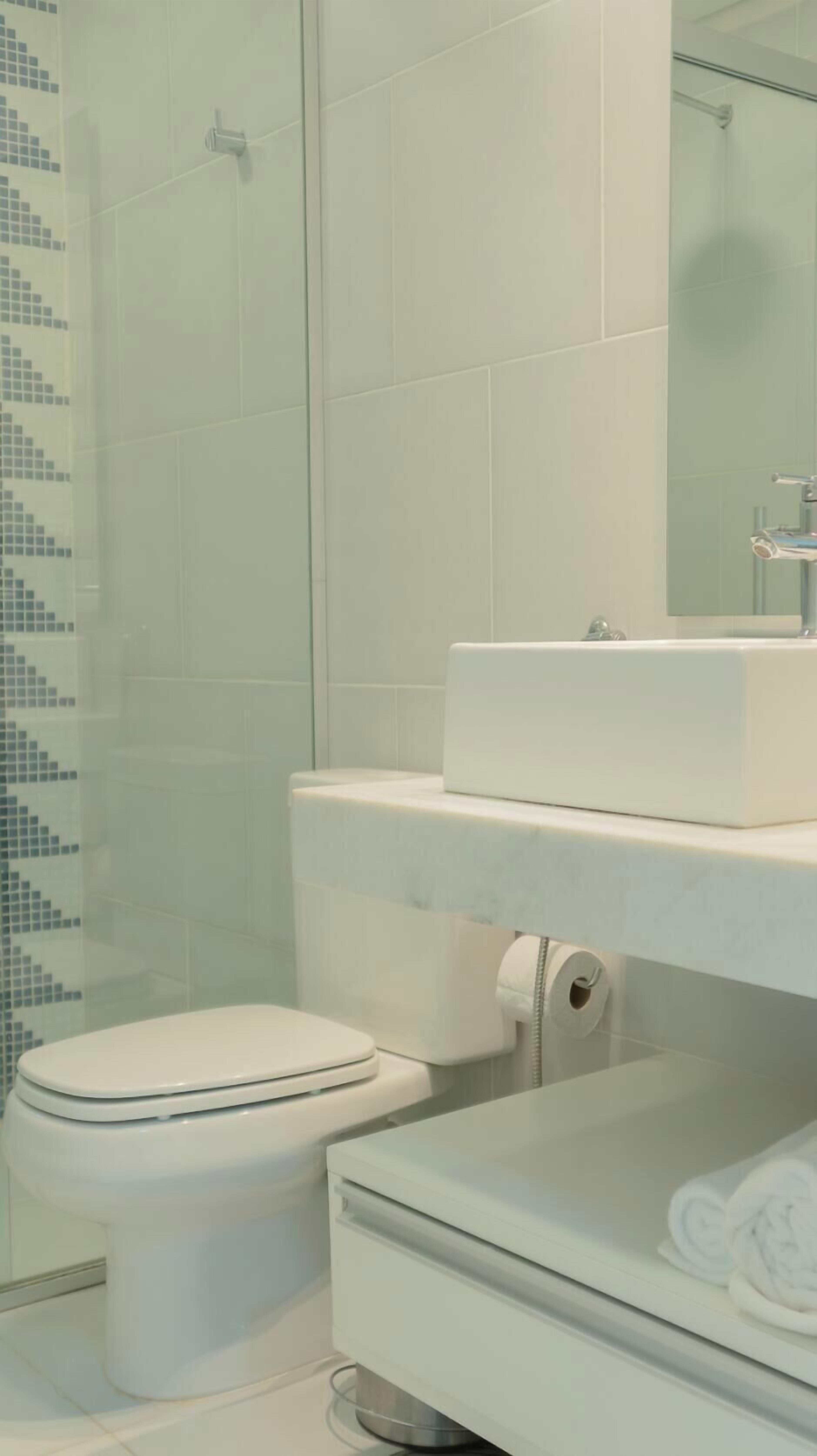 Ein Badezimmer mit Toilette, Dusche und Waschbecken mit Spiegel.