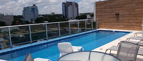 Una piscina al aire libre, sillones reclinables de piscina