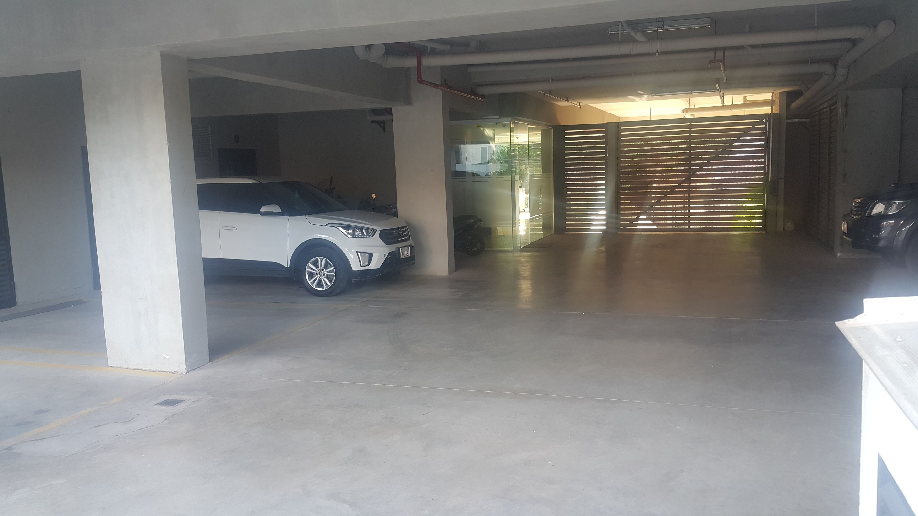 A parking garage with a white SUV parked under a concrete pillar.