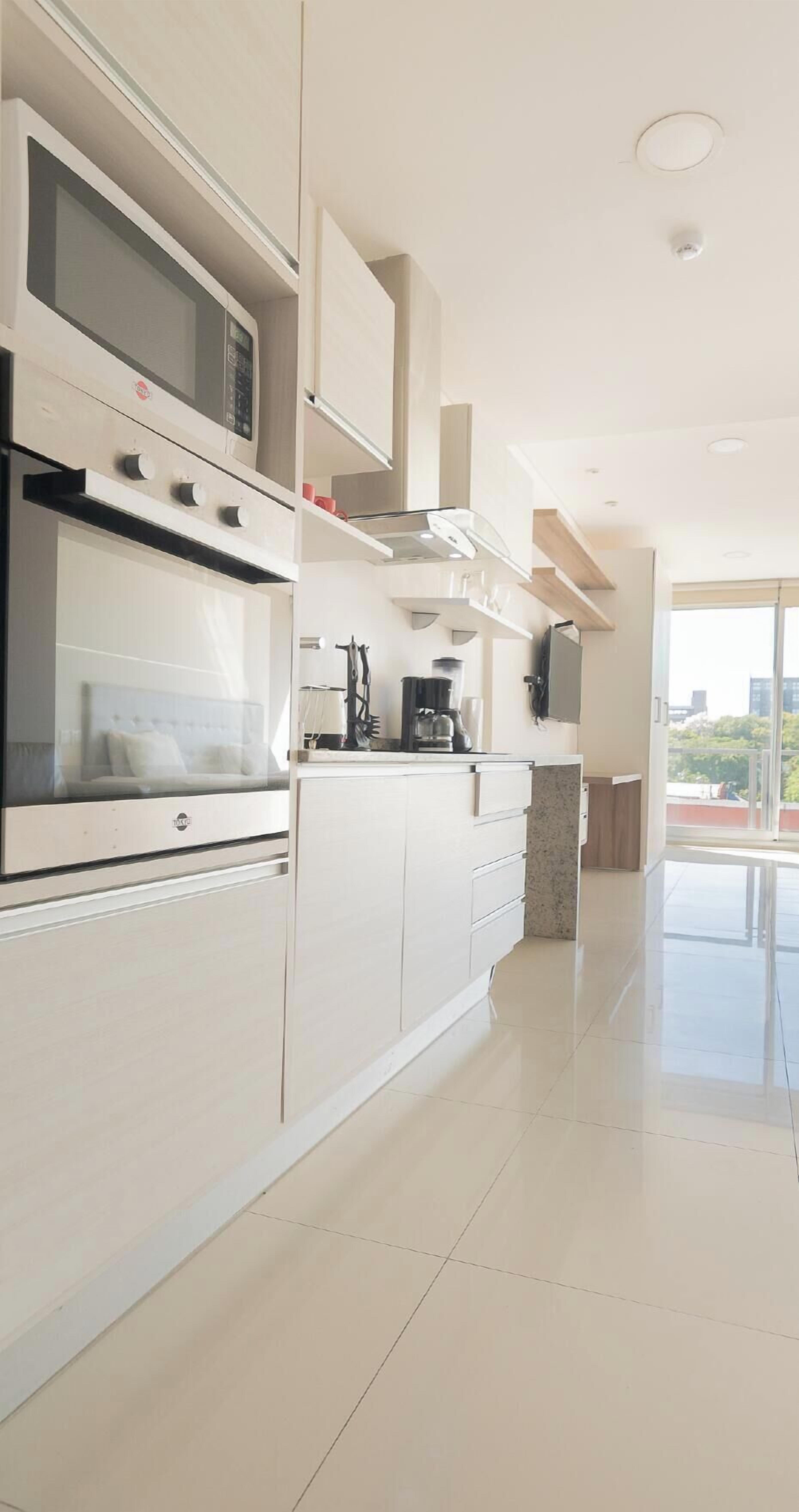 A modern kitchen with built-in appliances, a large window, and a clean, minimalist design.