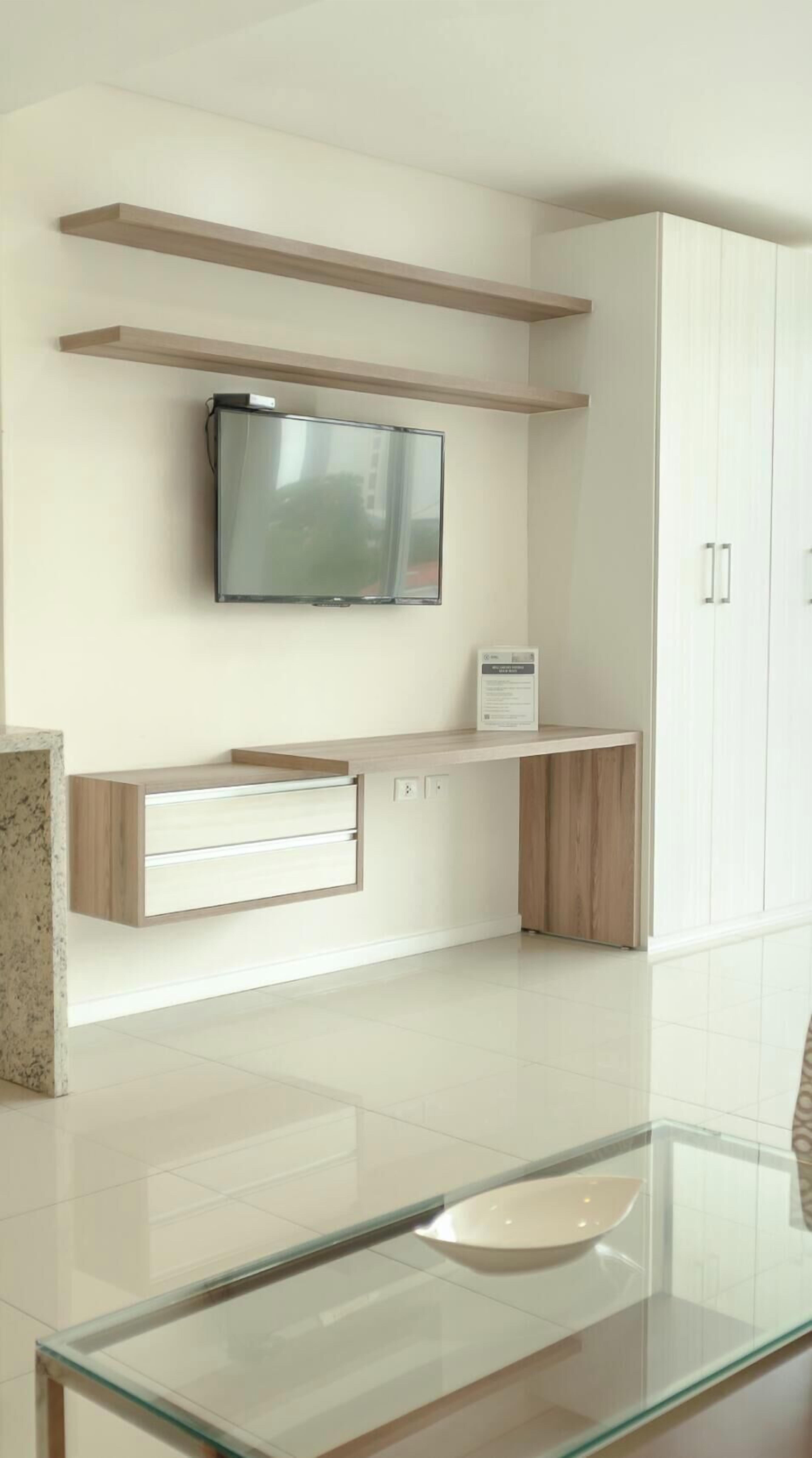 A modern kitchen with a built-in TV, wooden cabinets, and a glass-top table.