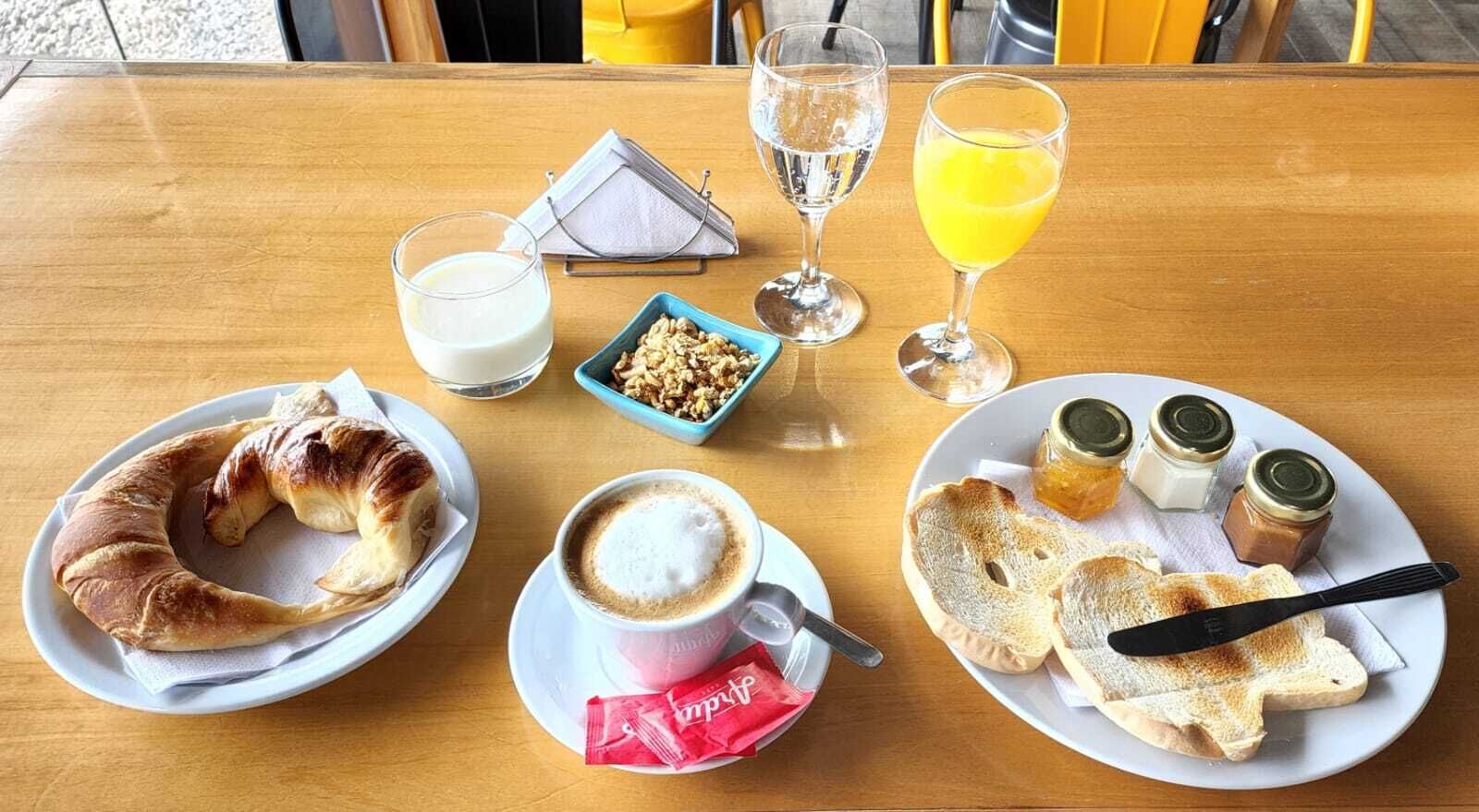 Una tavola imbandita con croissant, caffè, succo di frutta e condimenti.