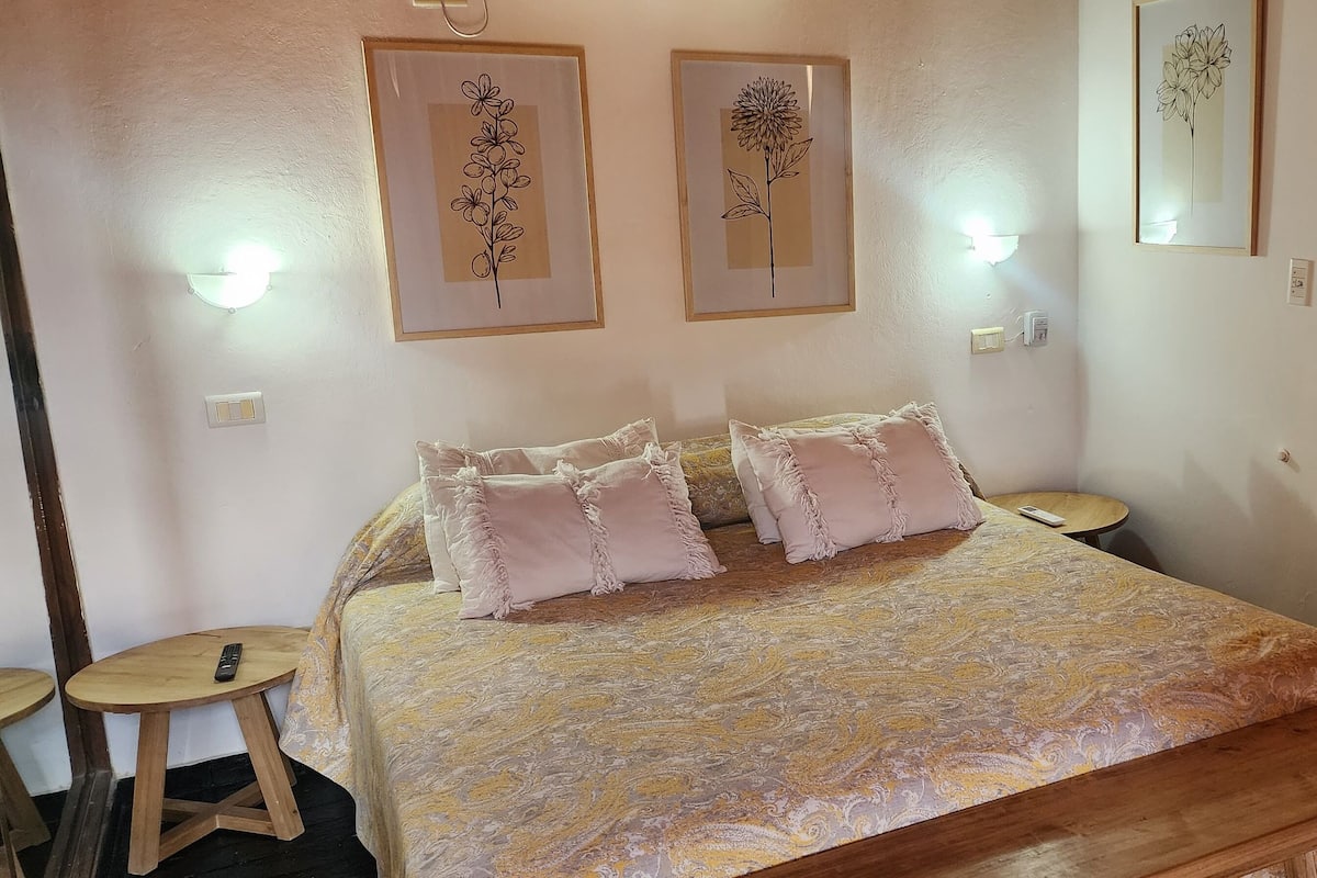 Une chambre à coucher comprenant un lit, des tables de chevet et des lampes fixées au mur.