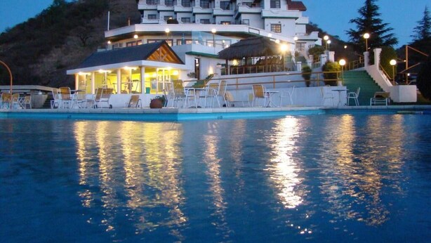 Un grand hôtel avec de nombreux étages, une piscine et des espaces extérieurs aménagés pour se détendre.
