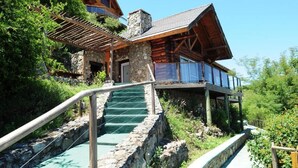 Une cabane en rondins avec des fondations en pierre, un revêtement extérieur en bois et un balcon en verre.
