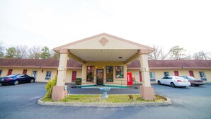 A motel with a covered entrance, a Coca-Cola sign, and a parking lot with several cars. - Sunset Motel (Egg Harbor Township)