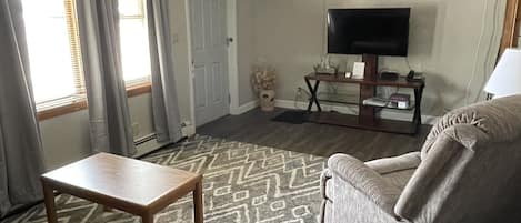 A living room with a sofa, armchair, and a television on a stand.