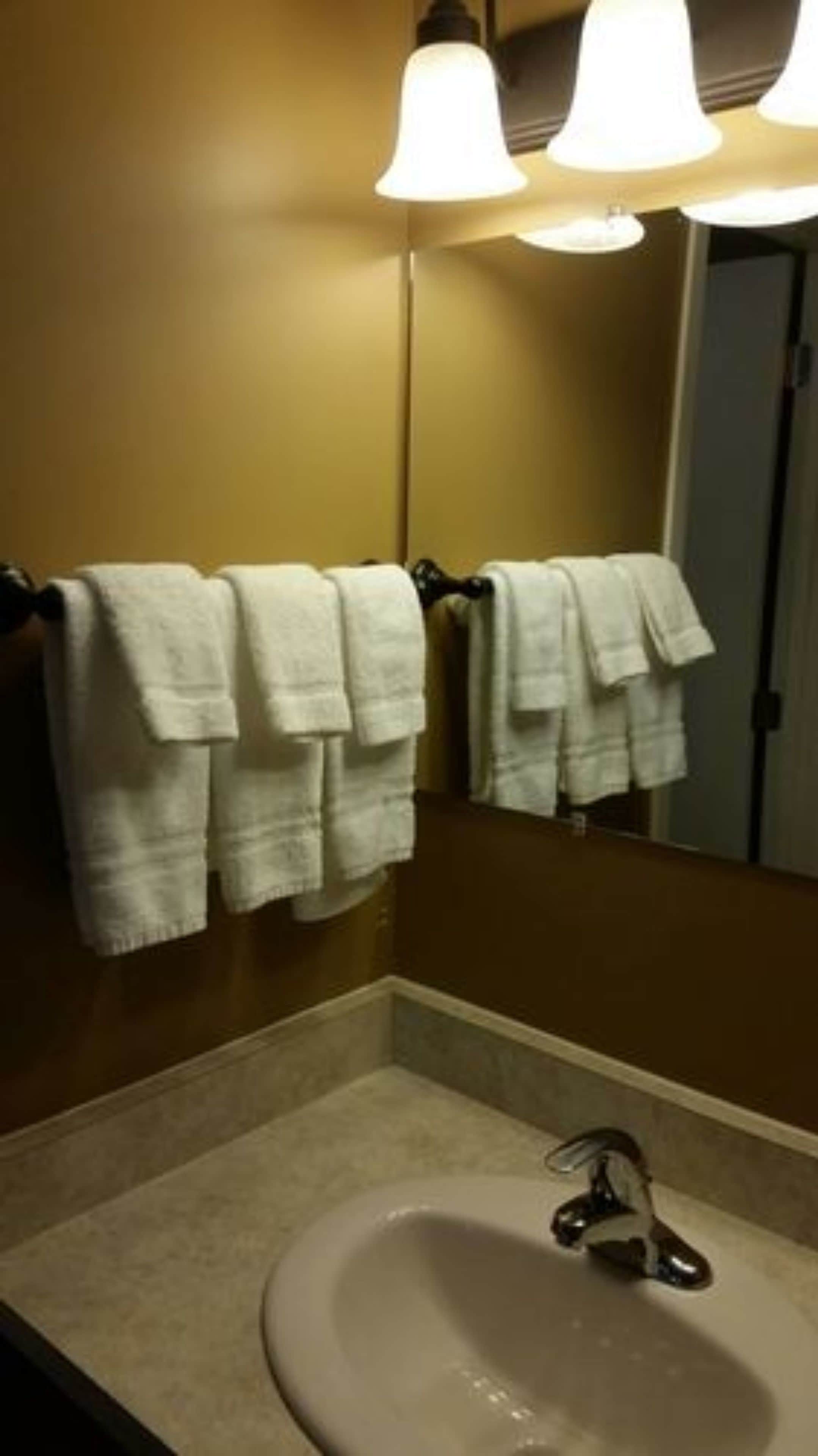 A bathroom with a sink, two towels hanging on a towel rack, and a mirror above the sink.