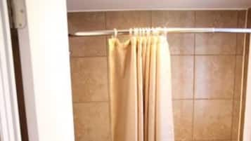A bathroom with a bathtub, toilet, and beige tiles.