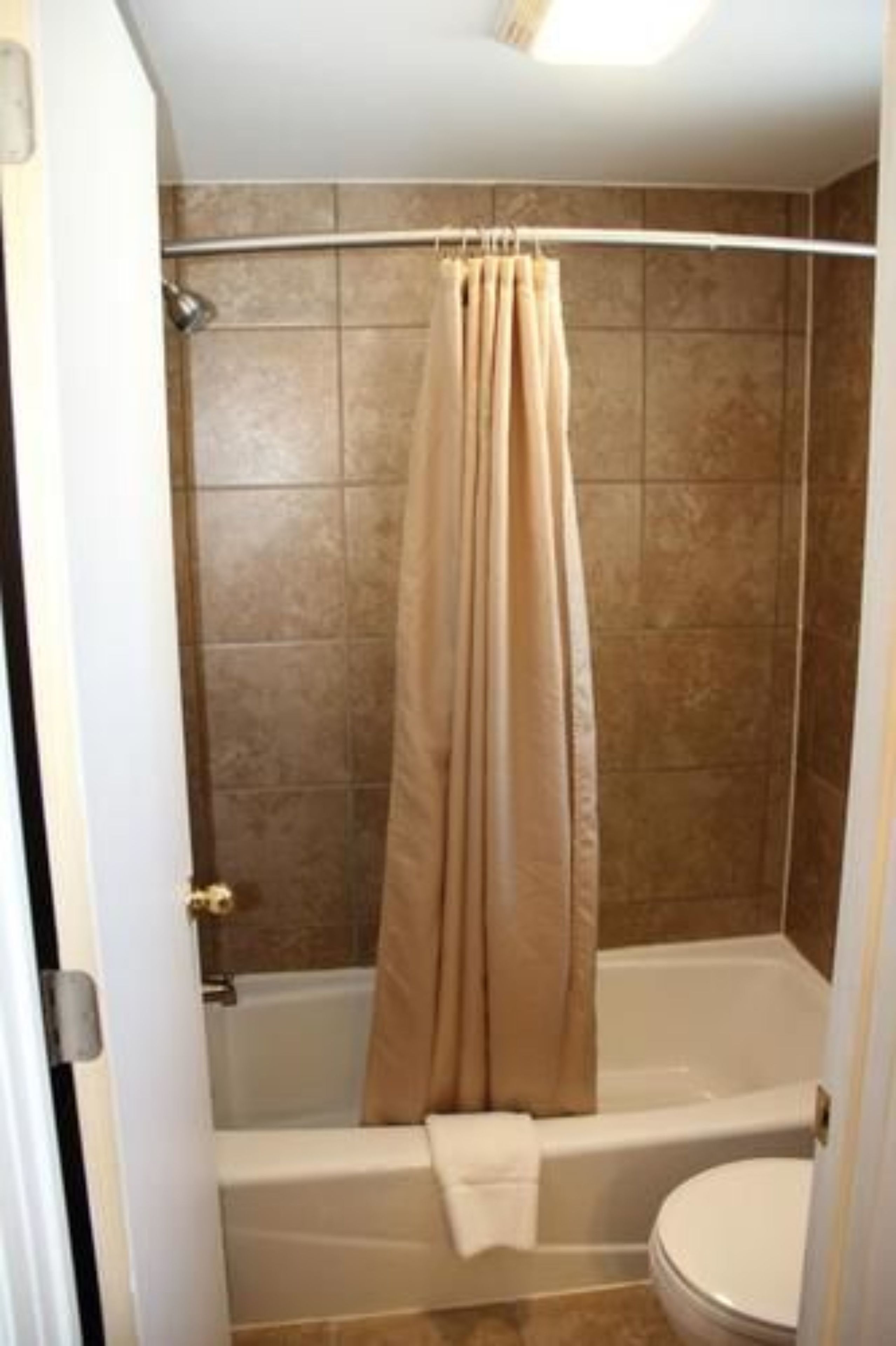 A bathroom with a bathtub, toilet, and shower curtain.