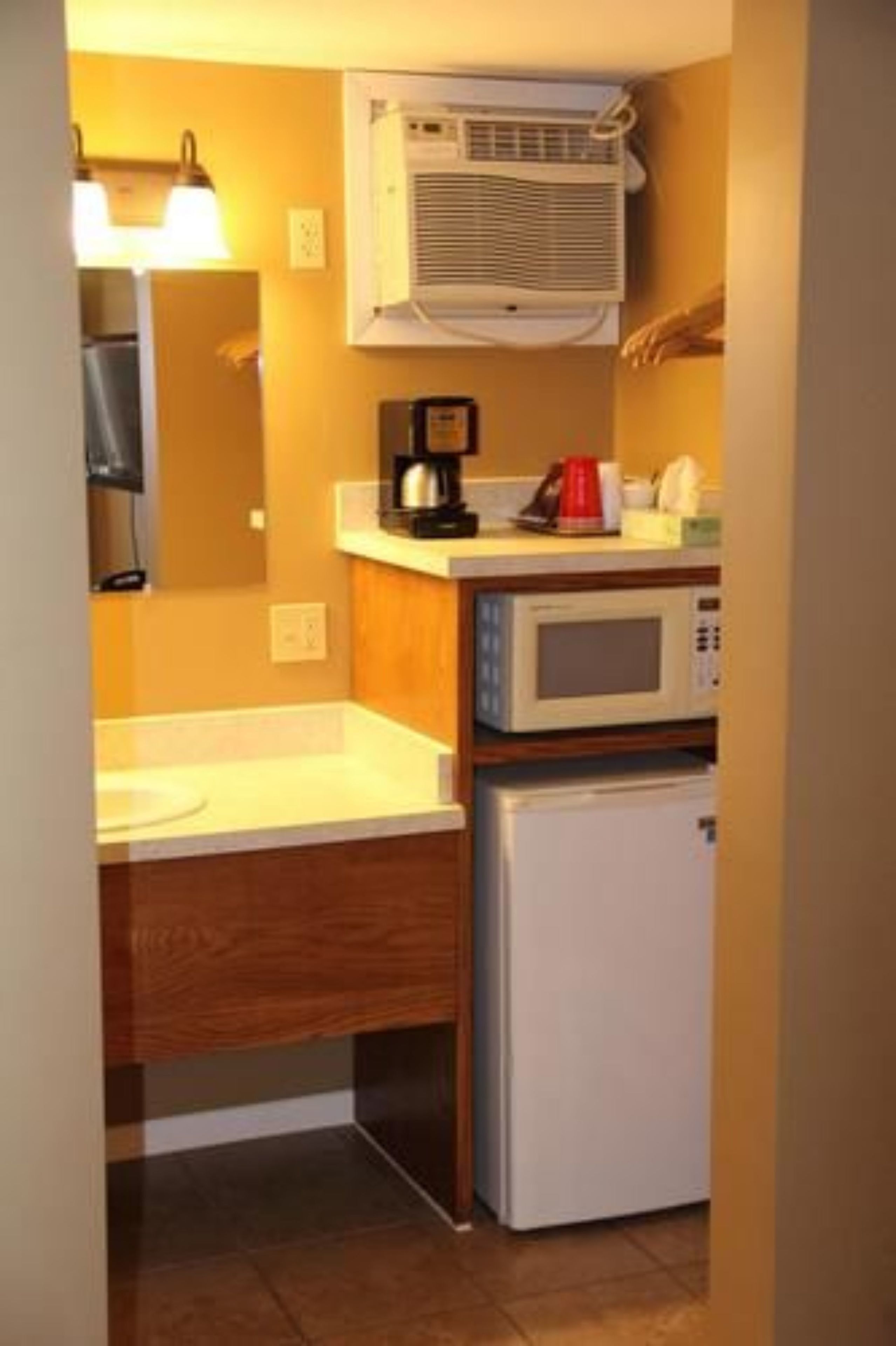 Una cocina compacta con microondas, cafetera y refrigerador.