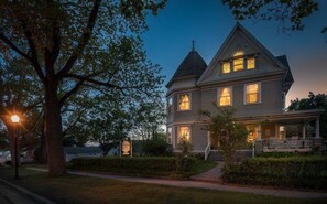 A two-story house with a wrap-around porch and a steeply pitched roof. - McConnell Inn (Green Lake)