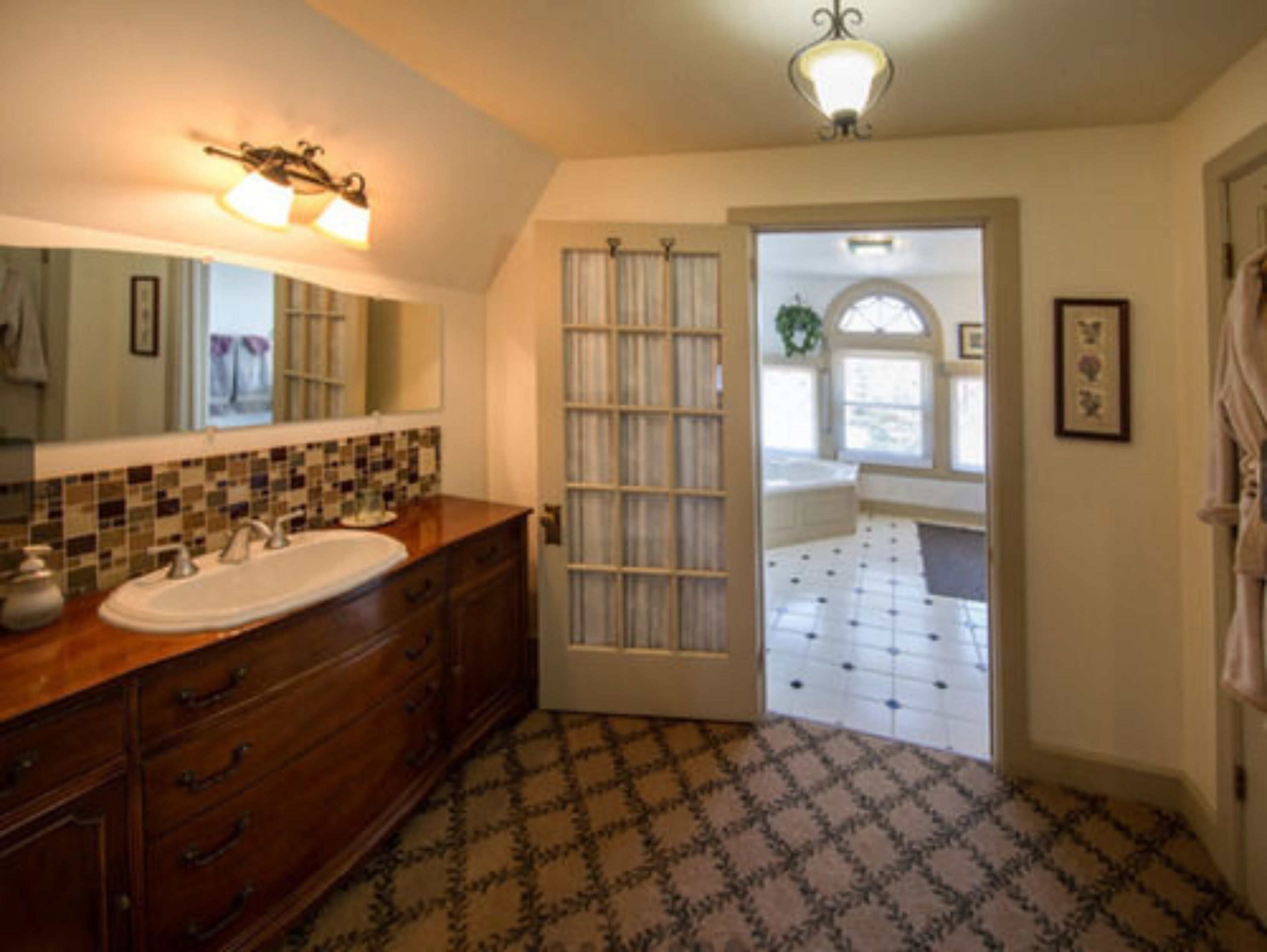 A bathroom with a wooden vanity, a white sink, and a tiled floor.