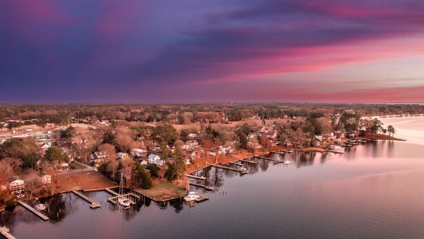 An aerial view of a lakeside community with docked boats, houses, and a bridge in the distance. - The Inn on Bath Creek (Bath)