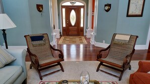 A living room with two wooden chairs, a sofa, a coffee table with a decorative item, and a patterned rug. - The Inn on Bath Creek (Bath)