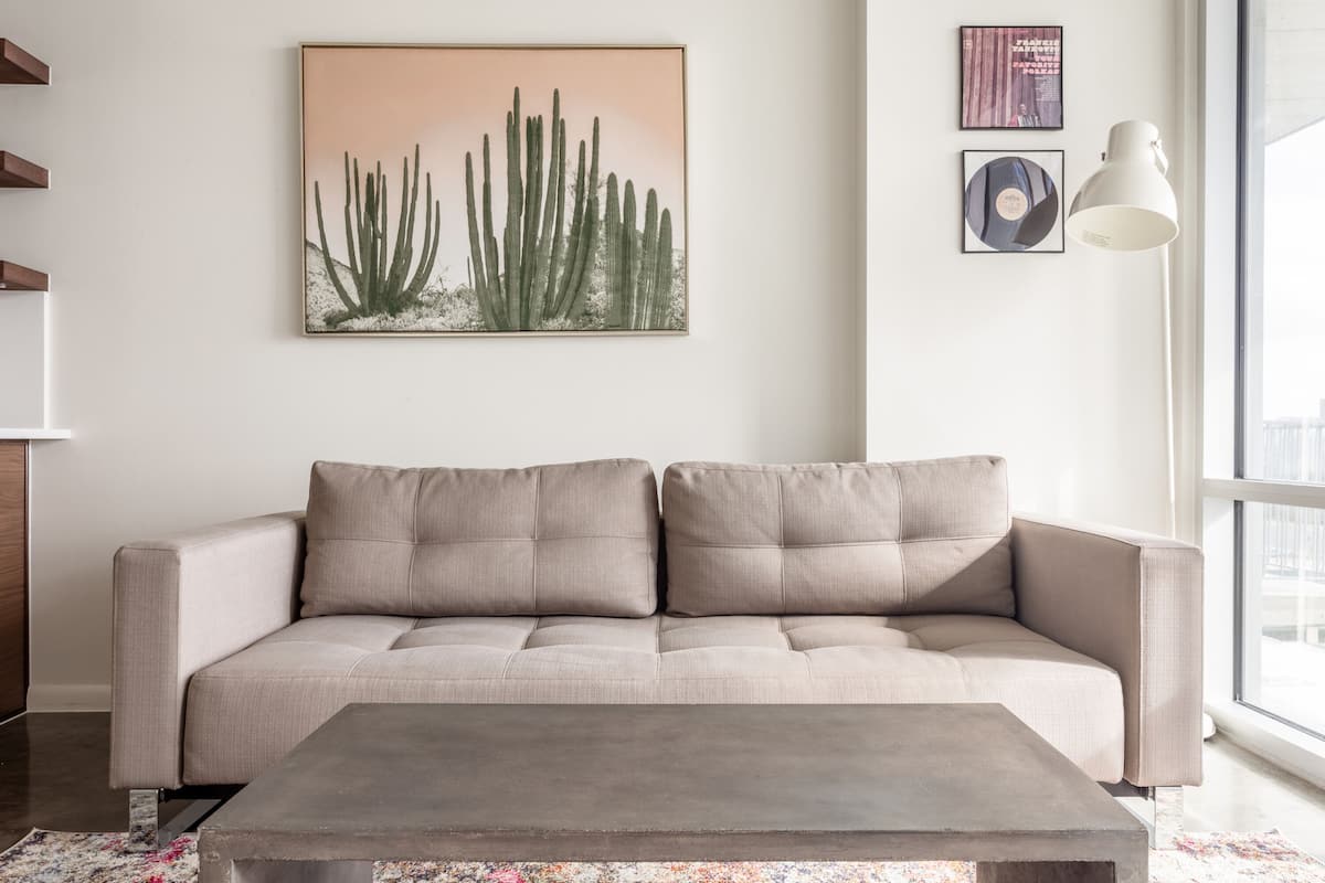 Ein modernes Wohnzimmer mit einem beigefarbenen Sofa, einem Couchtisch und einem großen Fenster, das für natürliches Licht sorgt.