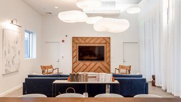 A modern conference room with a wooden accent wall, a large flat-screen TV, and a central table with books.