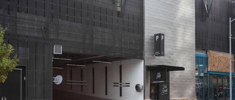 Un edificio moderno con entrada a un estacionamiento, un cartel que indica '2nd Street' y un letrero que dice 'PARKING STAIRWELL'.