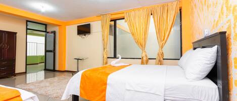 A hotel room with two beds, a TV, and a large window with curtains.