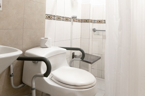 Un baño con inodoro, lavamanos y zona de ducha.