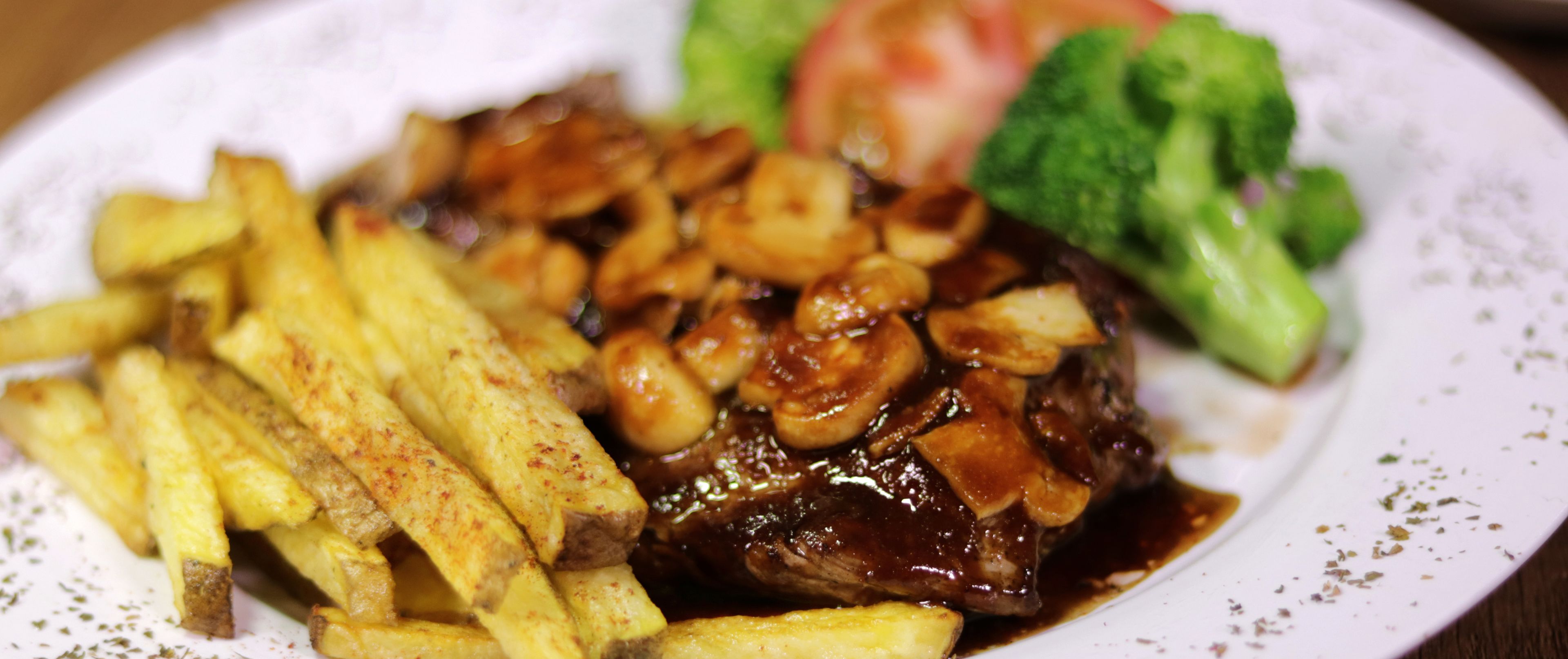 Un plato con bistec, papas fritas y brócoli.
