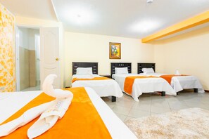 A hotel room with three beds, each with white and orange bedding, a fluffy beige rug, and a painting on the wall. - Hotel Miraflores (Ibarra)