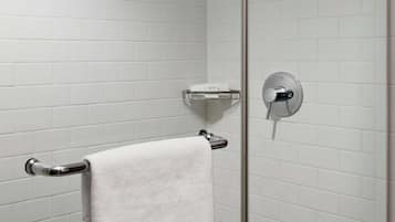 A glass-enclosed shower with white tiles, a towel rack, and a control panel.