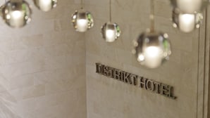 Un letrero para 'DISTRIKT HOTEL' con un diseño moderno y lámparas esféricas colgantes.
