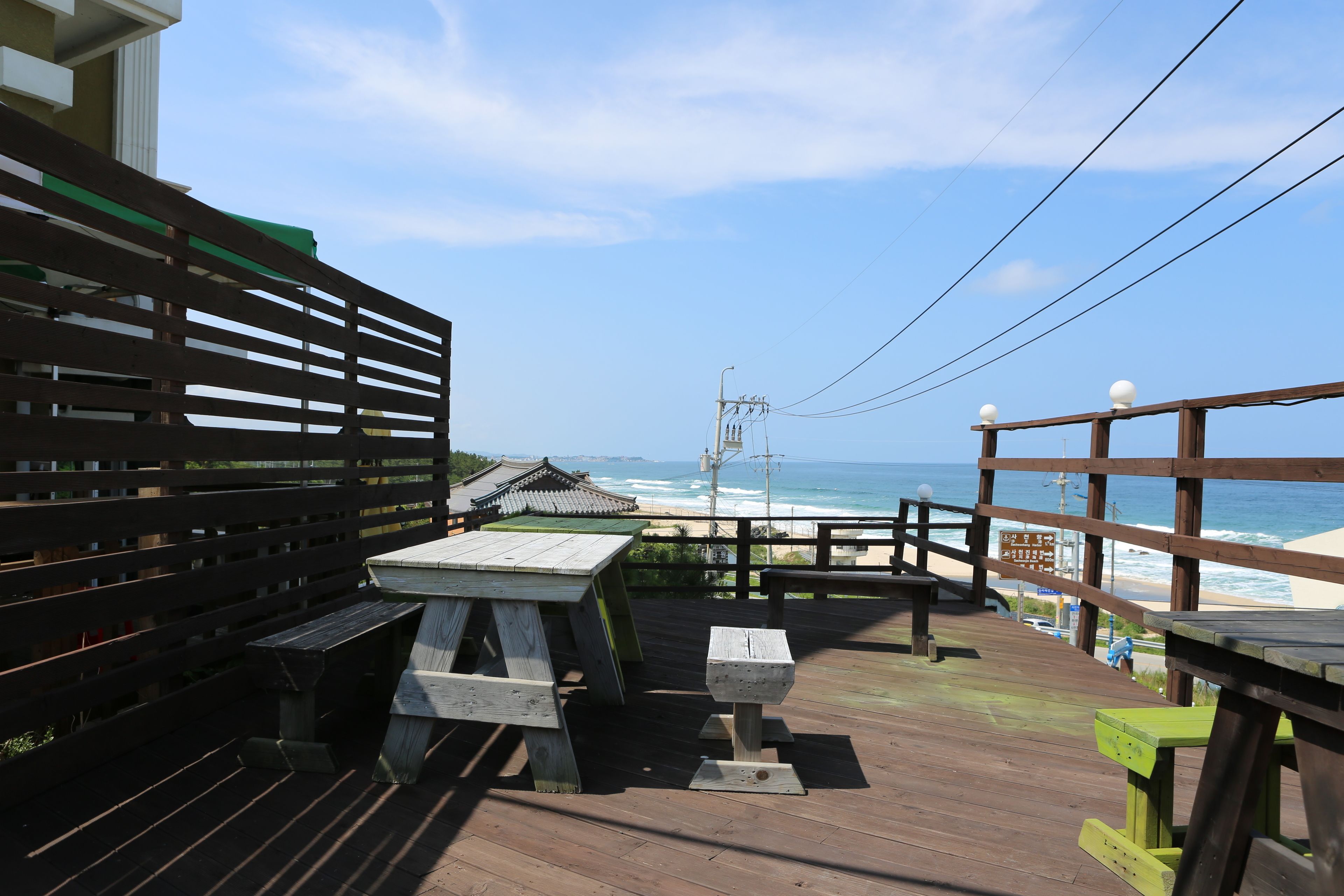 A wooden deck with picnic tables and a view of the beach.