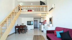 A modern living space with a wooden staircase, a dining area, a kitchen, and a red sofa. - Seaview Pension (Gangneung)